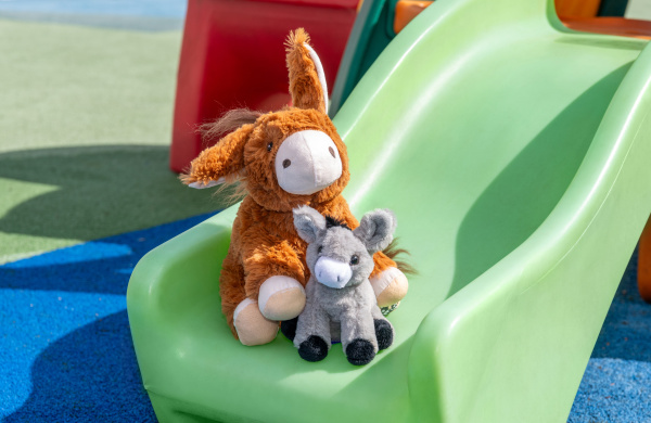 Two donkey soft toys on a slide.