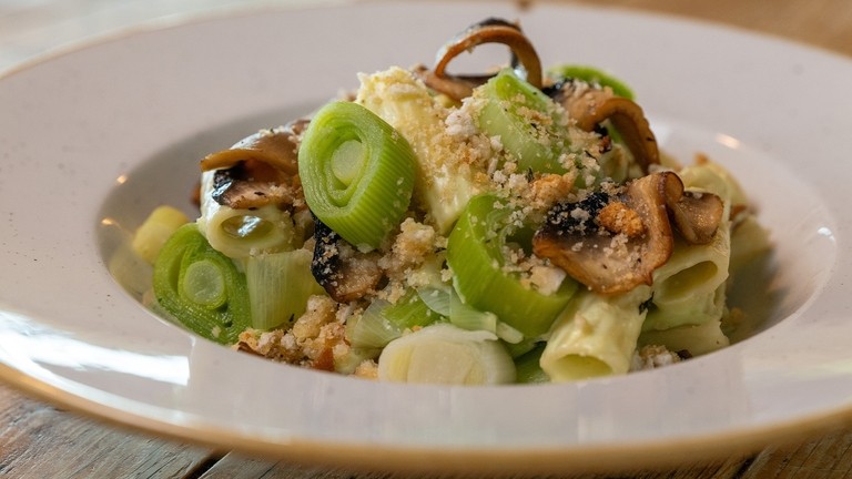 A bowl with leek and mushroom rigatoni pasta