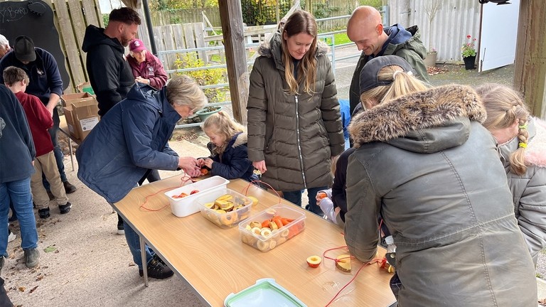 A group of families creating food enrichment on a table for donkeys