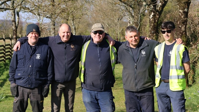 An image of five men stood in a line, smiling and looking toward the camera.