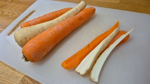 A close up of chopped up strips of carrot and parsnip