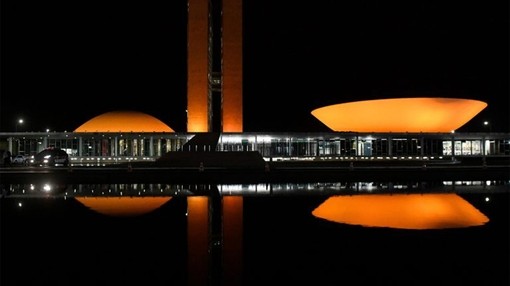A congress building lit up orange in the dark