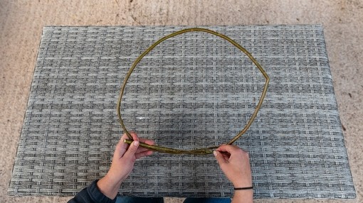 A pair of hands holding wooden twigs shaped into a circle above a placemat