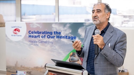 An image of a man presenting and talking in front of a podium holding a laptop and a sign behind him which reads: "Celebrating the Heart of Our Heritage"