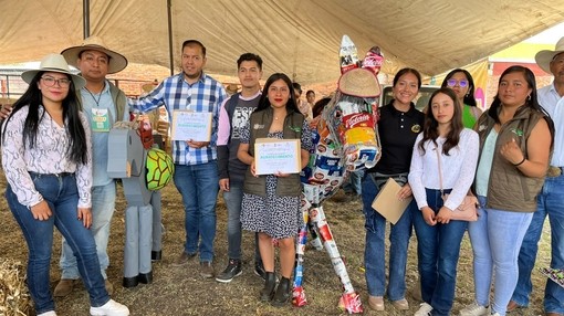 An image of a group of people standing together with two donkey statues as the pose and hold certificates.