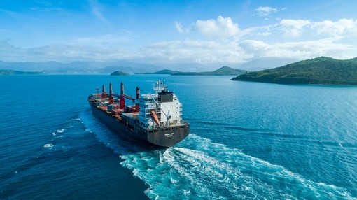 An image of a cargo shipping boat sailing away from the camera